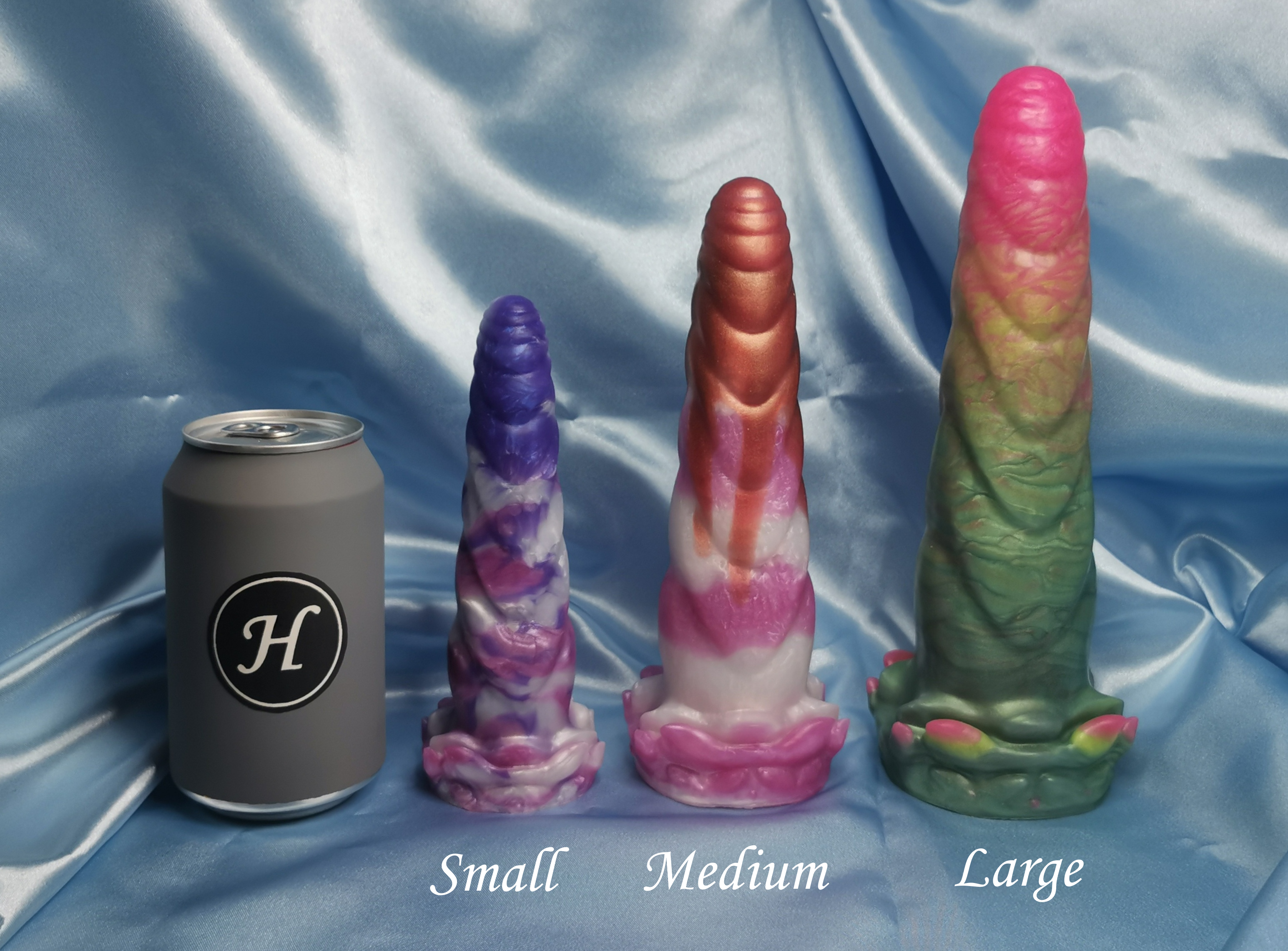 Three colorful dildos labeled 'Small', 'Medium', and 'Large' next to a can on a blue fabric background.